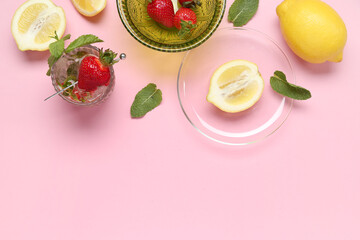 Glass of fresh lemonade with strawberry and lemon on pink background