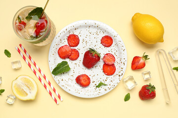 Glass of fresh lemonade with strawberry and lemon on beige background
