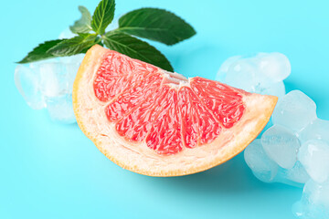 Grapefruit piece with ice cubes and mint on blue background