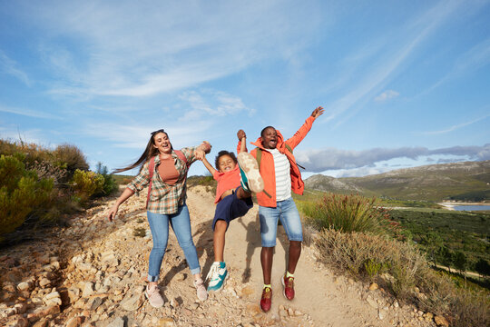 Young family playing on hiking trail with clouds and mountain views