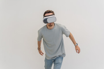 Futuristic man wearing virtual reality glasses interacts with the air in an isolated gray...