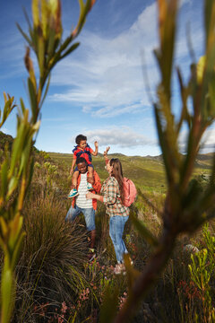 Young multi-racial family on scenic hike with clouds and lush greenery