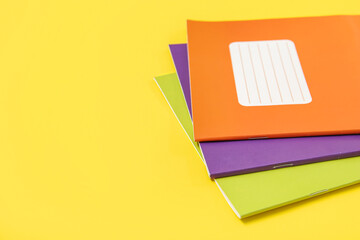 Different colorful notebooks on yellow background