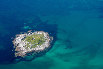 une petit île au milieu d'une eau bleue, verte et transparente