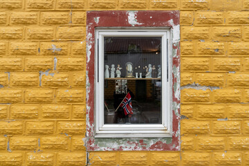 une fenêtre sur un mur jaune , avec des objets et un fagnon norvégien vu à travers  - 622064023