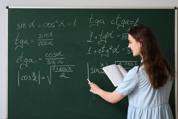 Female Math teacher writing on chalkboard in classroom