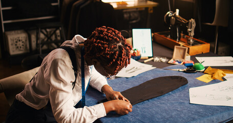 African american tailor preparing fabric to create tailored suit in atelier, working with crafting...