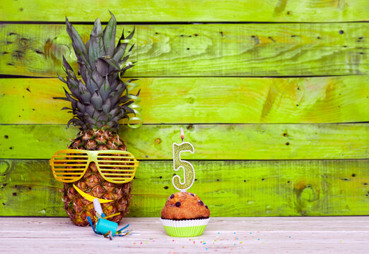 Creative card postcard happy birthday with number  5. Background character pineapple in festive glasses. Copy space anniversary card on yellow colorful wooden background.