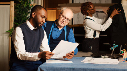 Senior couturier using meter to take measurements for client order, ensuring perfect size for...