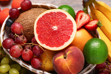 Wicker bowl with different fresh fruits, closeup