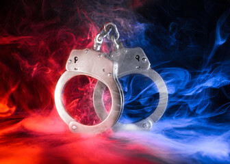 Pair of locked handcuffs with red and blue smoke.
