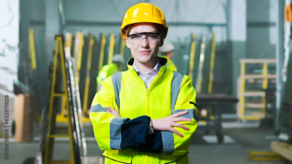 Wall mural portrait shot of pretty caucasian woman in hardhat and uniform standing at manufactory site, taking 