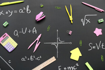 Different stationery on black chalkboard with formulas