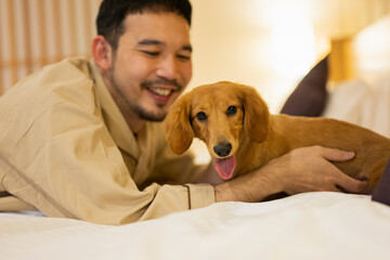 ホテルのベッドで飼い犬と戯れる男性