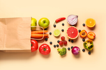 Paper bag with different fresh fruits and vegetables on orange background