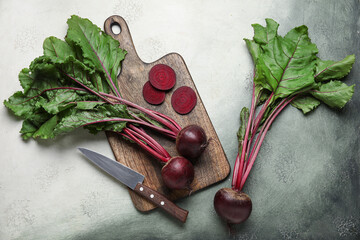 Cutting board with fresh cut beetroots and knife on grey grunge background