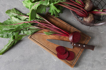 Cutting board with fresh cut beetroot and knife on grey grunge table
