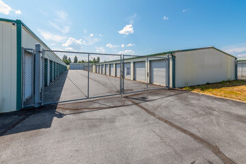 Garage storage units for rent behind a chain link fenced gate at a storage complex business.