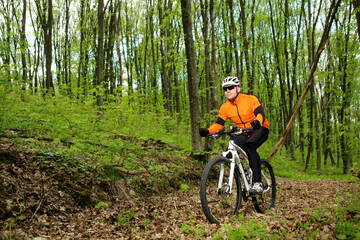 Fototapeta na wymiar Biker in orange jersey on the forest road
