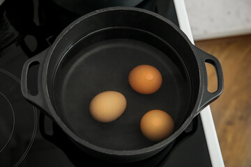 Chicken eggs boiling in cooking pot, closeup