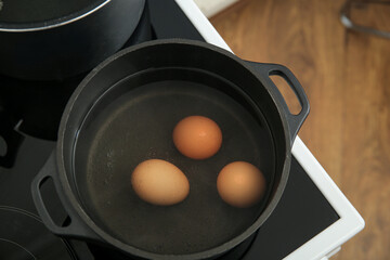 Chicken eggs boiling in cooking pot, closeup