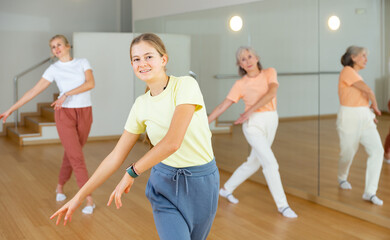 Obraz premium Young girl performing aerobic dance during group training with her mother and grandmother.