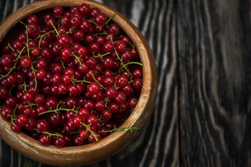 Fresh red currants in plate on wooden table
