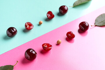 Sweet cherries with halves and leaves on colorful background