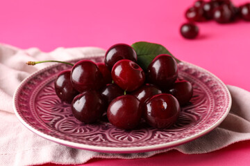 Plate with sweet cherries on colorful background