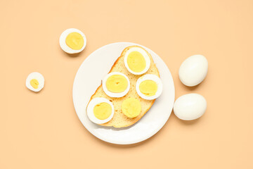 Plate of toast with boiled eggs on orange background