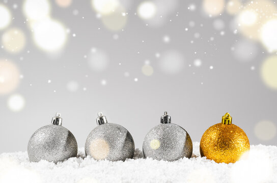 silver and golden decorative christmas balls on snow against grey festive background