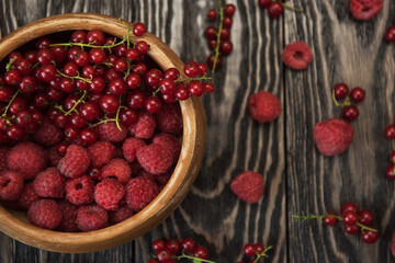 Fresh berries raspberry and red currant in bowl on wooden table