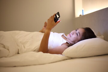 young woman use phone when her sleeping on bed  at night.