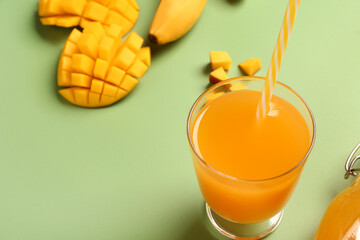 Glass of fresh mango juice on green background