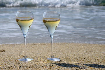 Summer time in Provence, two glasses of cold champagne cremant sparkling wine on sandy beach near Saint-Tropez in sunny day, Var department, France