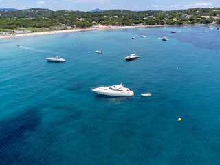 Fototapeta na wymiar Aerial view on boats, crystal clear blue water of legendary Pampelonne beach near Saint-Tropez, summer vacation on white sandy beach of French Riviera, France