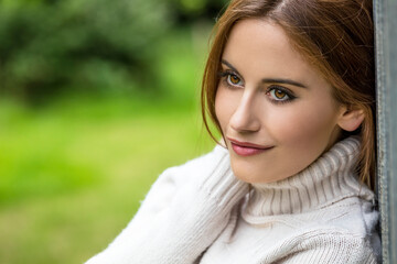 Obraz premium Outdoor portrait of beautiful thoughtful girl or young woman with red hair wearing a white jumper