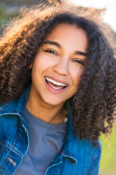 Outdoor portrait of beautiful happy mixed race African American girl teenager female young woman smiling laughing with perfect teeth