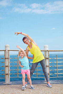 Look Good, Feel great! Full length portrait of smiling mother and child in fitness outfit stretching on embankment