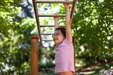 Obraz premium Little girl playing on the playground in the park on a sunny day