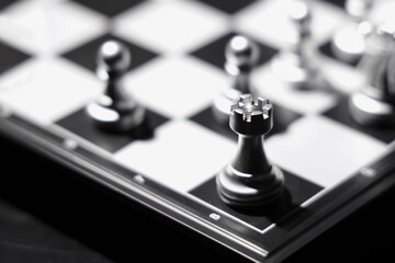 Silver chess pieces on game board, closeup