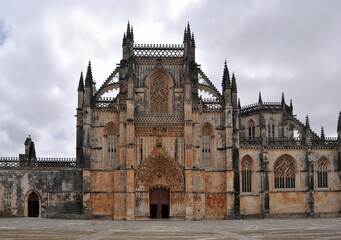 Fototapeta na wymiar Mosteiro da Batalha, Leiria, Portugal, céu nublado, entrada frontal do edificio