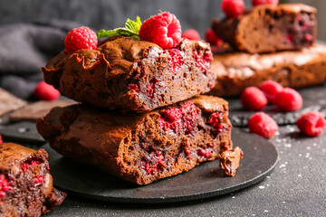 Board with pieces of raspberry chocolate brownie on black table
