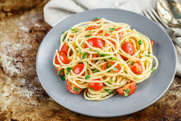 Spaghetti pasta with cherry tomatoes and parsley on rustric background