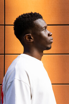 Serious young black man standing near wall