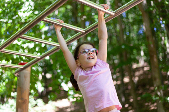 Little girl doing pull-ups on a horizontal bar in the park