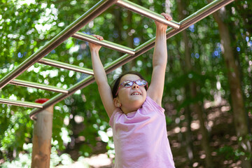 Little girl on the playground in the park. The girl is wearing glasses.