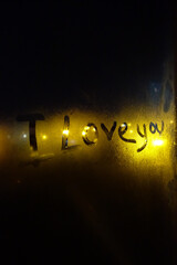 "I love you" lettering with mist on the balcony window at night