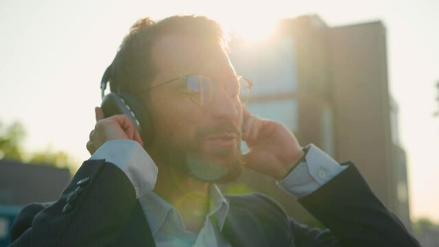 Excited Caucasian businessman listen song dance to music in headphones outside active happy business man enjoy singing in city sunlight listening sound dancing in earphones take office break dancing