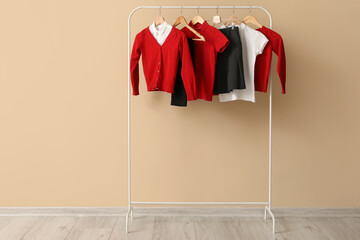 Rack with stylish school uniform against color wall